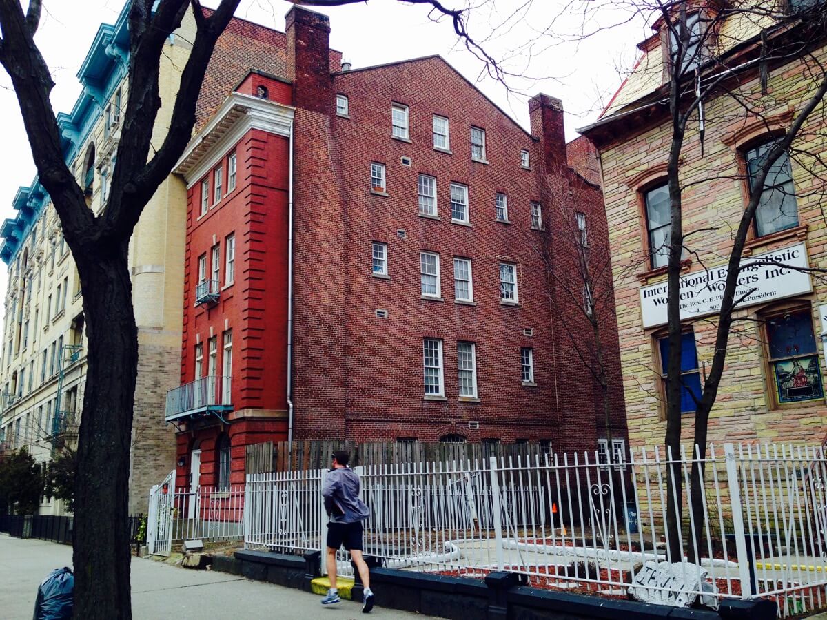 This mid-19th century red brick behemoth at 477 Washington Avenue in Clinton Hill had its stoop removed and facade altered in the early 20th century. Photo by Cate Corcoran
