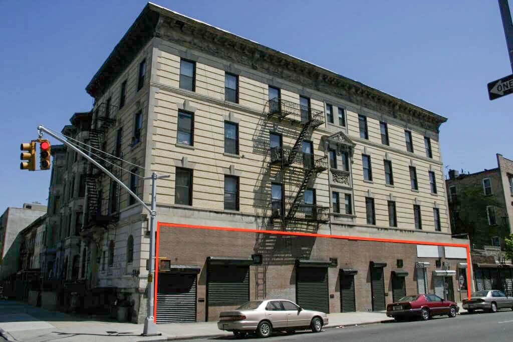 The building before renovation, with its previously bricked-in retail spaces (outlined in red)