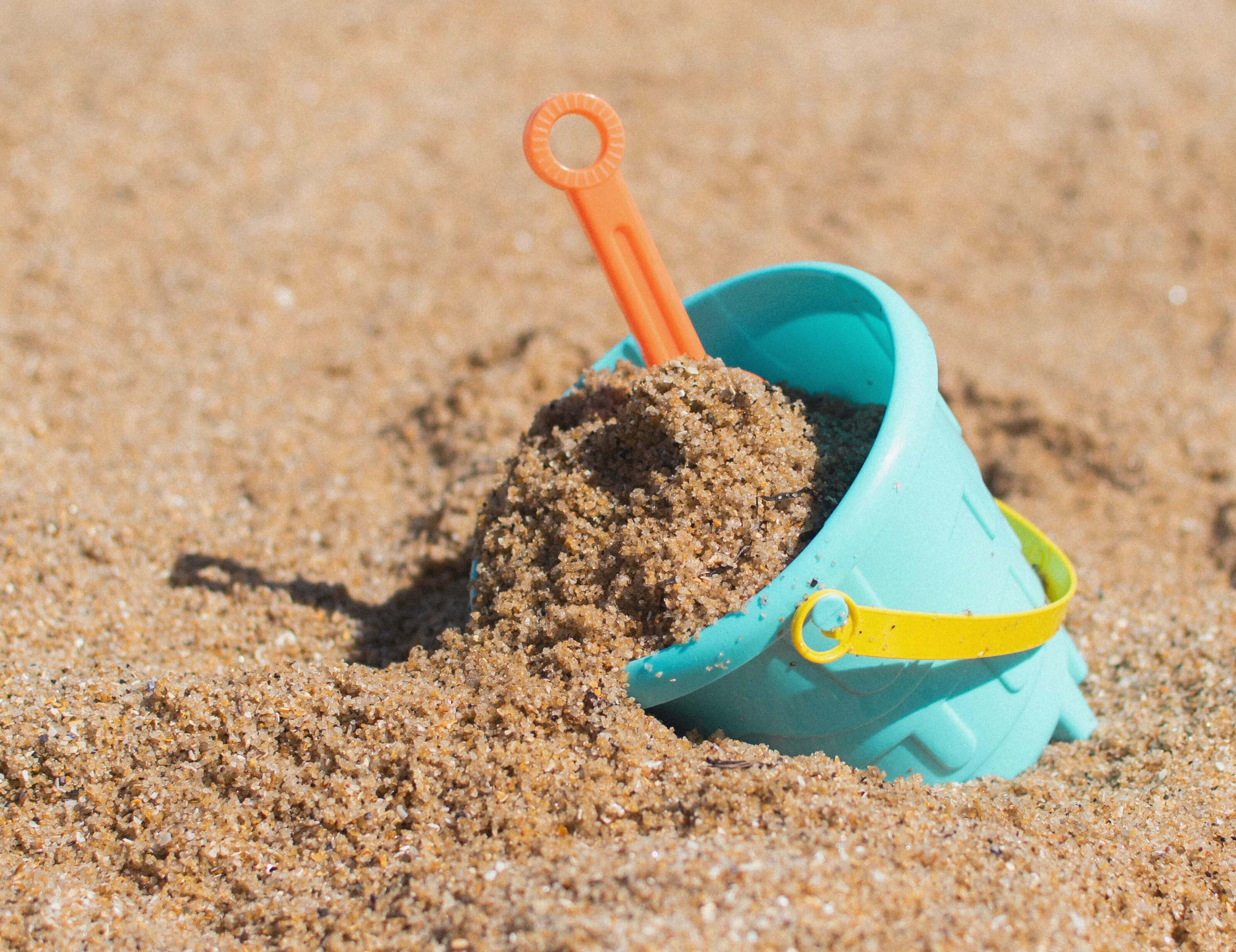 child's bucket and shovel in sand
