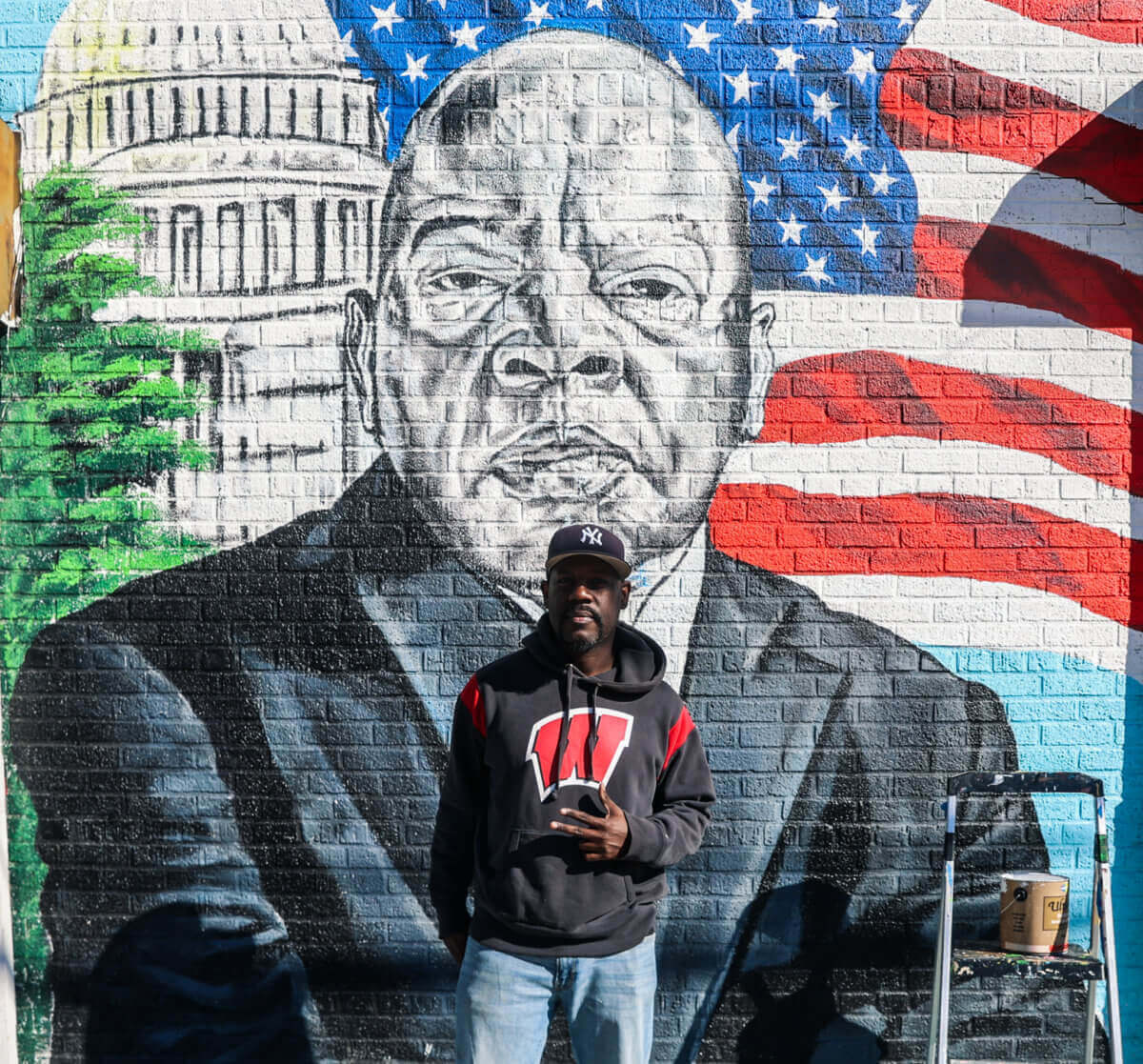 artist in front of mural