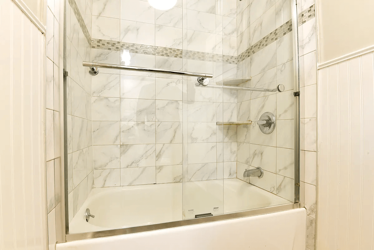 bath with beadboard and glass shower doors