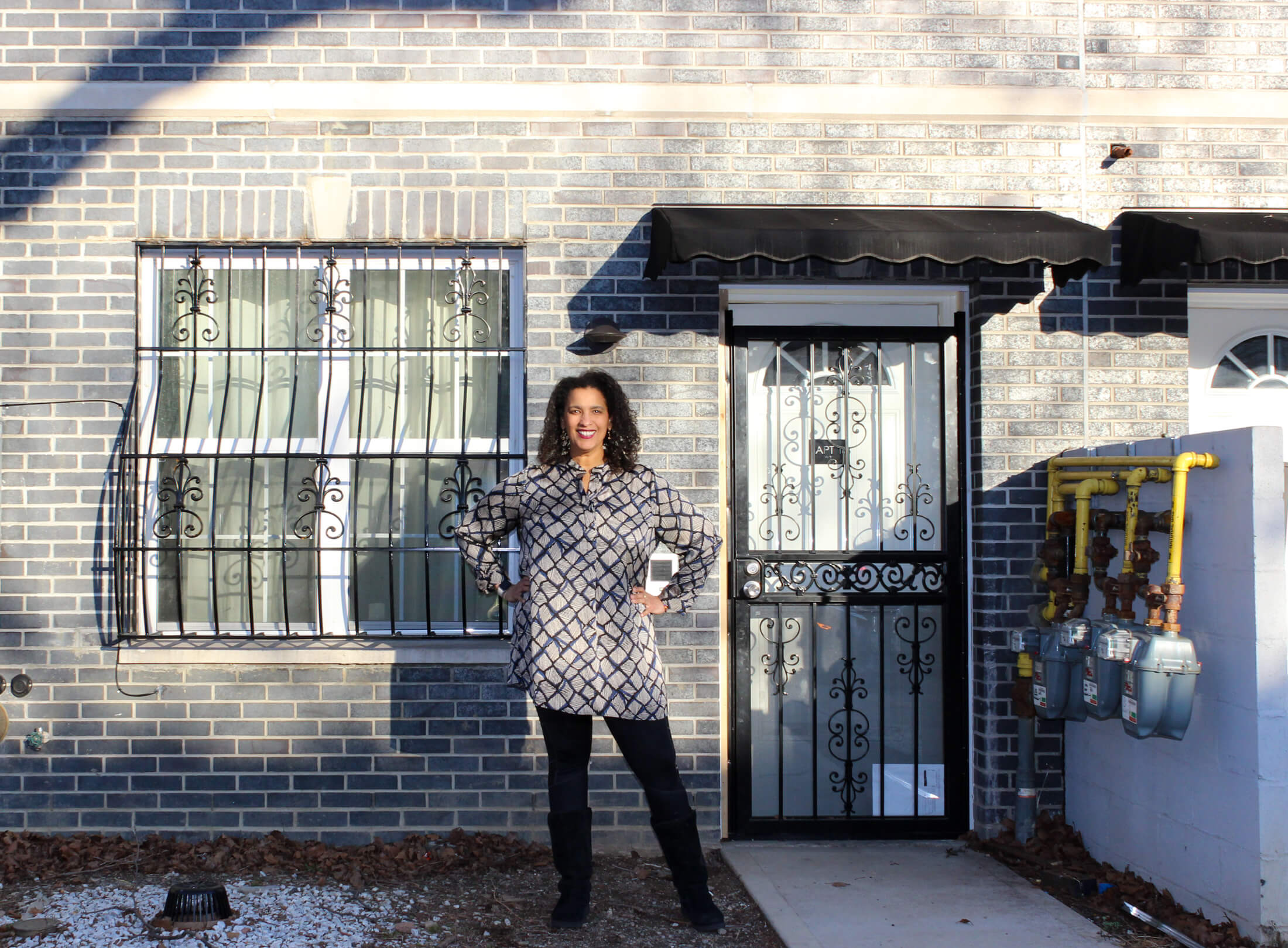 owner standing outside her brick home