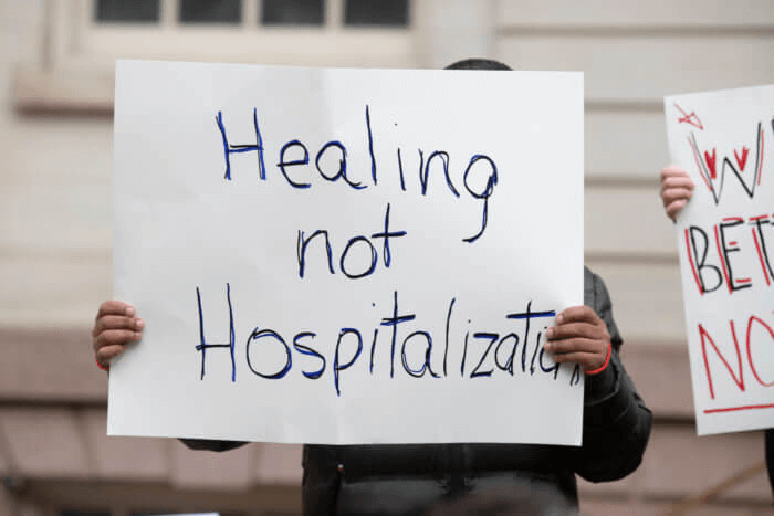 protest sign saying healing not hospitalization
