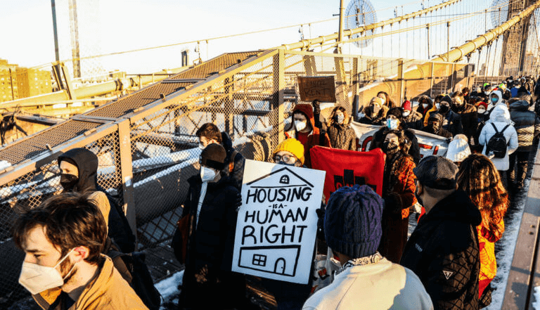 people with signs marching on the brooklyn bridge