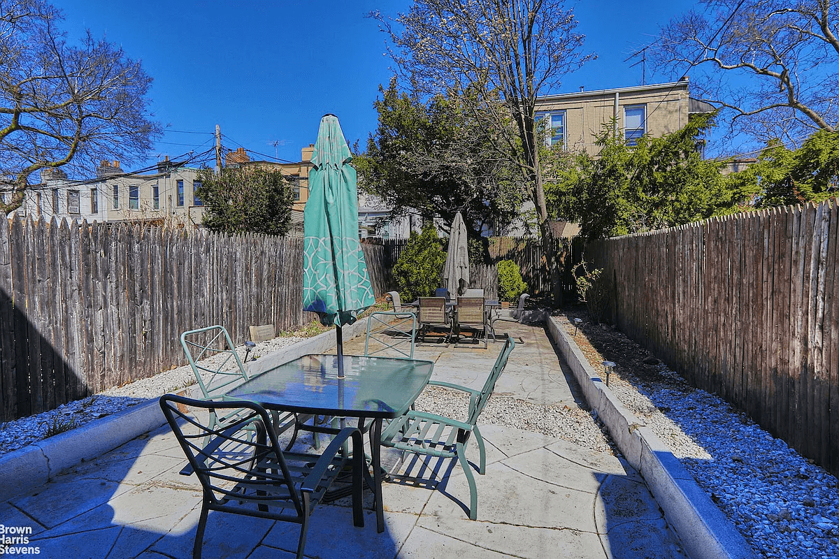 paved rear yard with planting beds around the perimeter