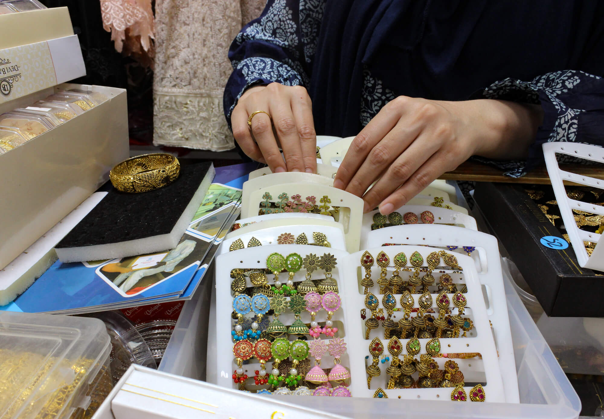 a woman sorts through a bin of jewelry