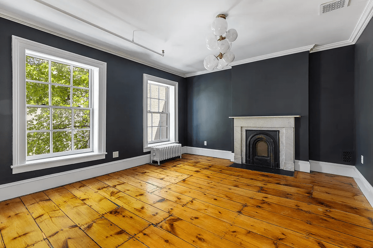 bedroom with wide floorboards and a mantel