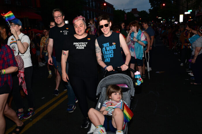 a family with a child in a stroller holding a pride flag