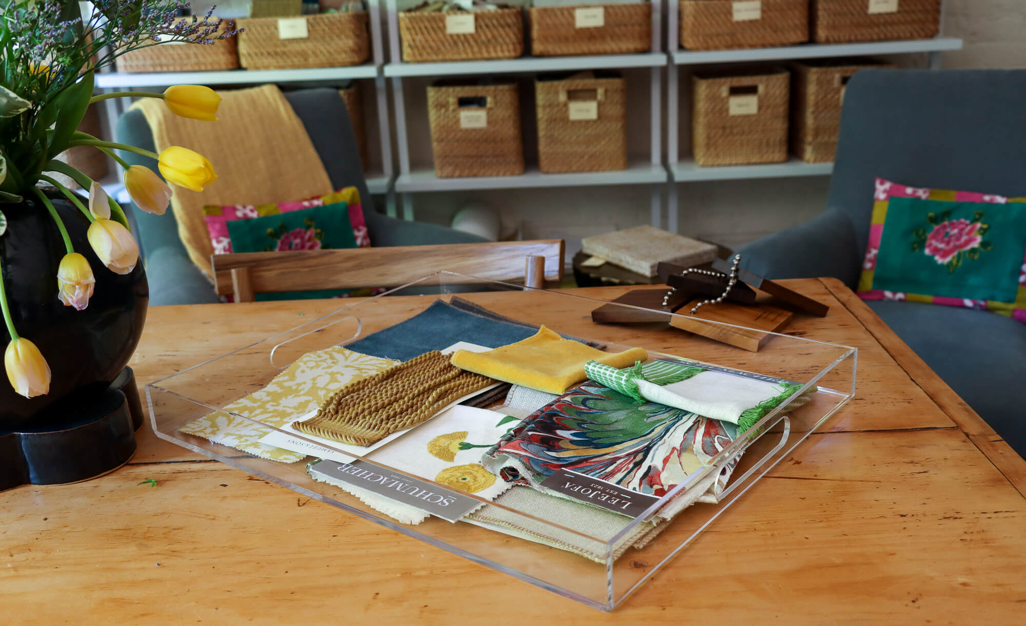 fabric samples in a clear tray on a wood table