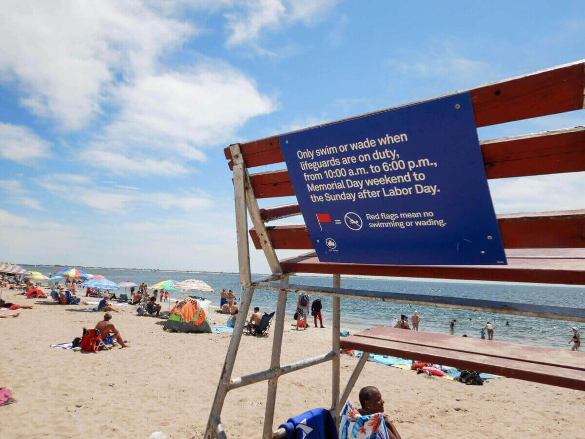 sign about lifeguard duty hours on the back of a chair in coney island