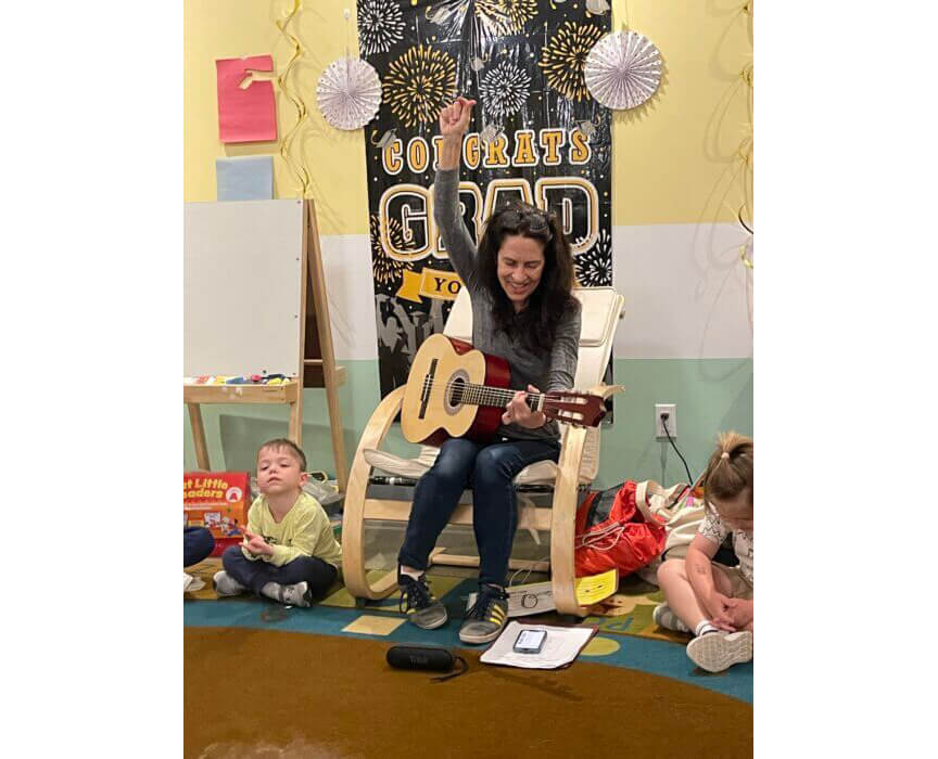 playing a guitar with children watching