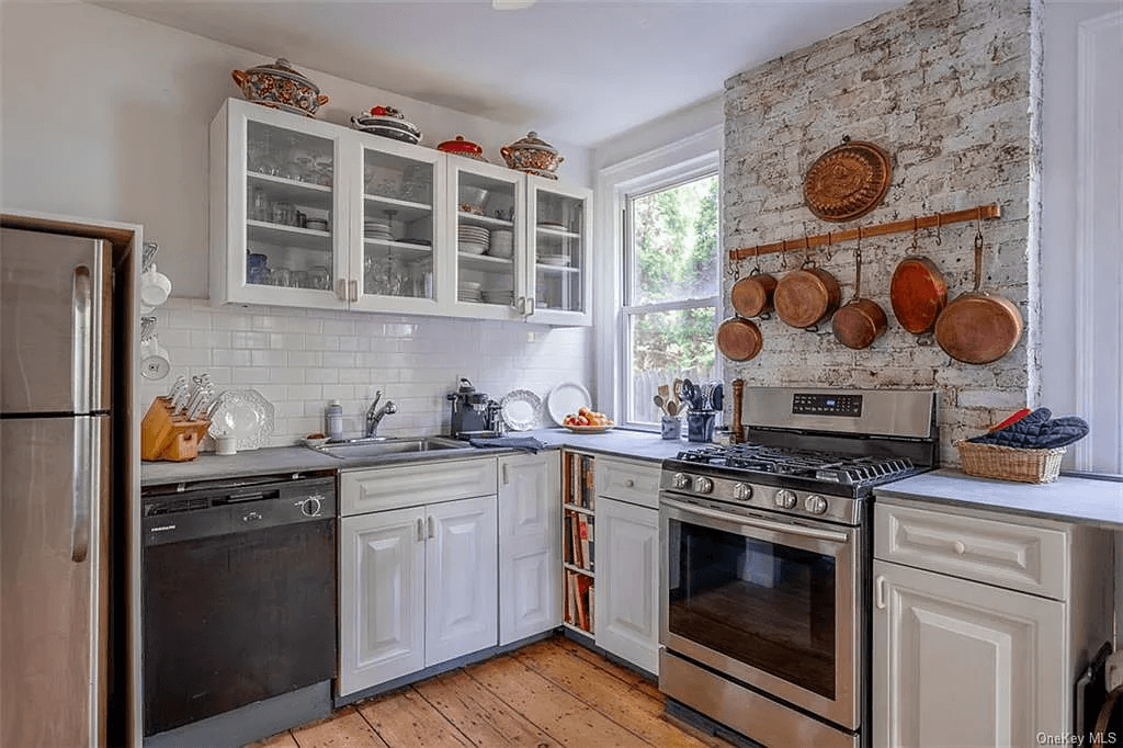 kitchen with exposed brick chimney wall and white cabinets