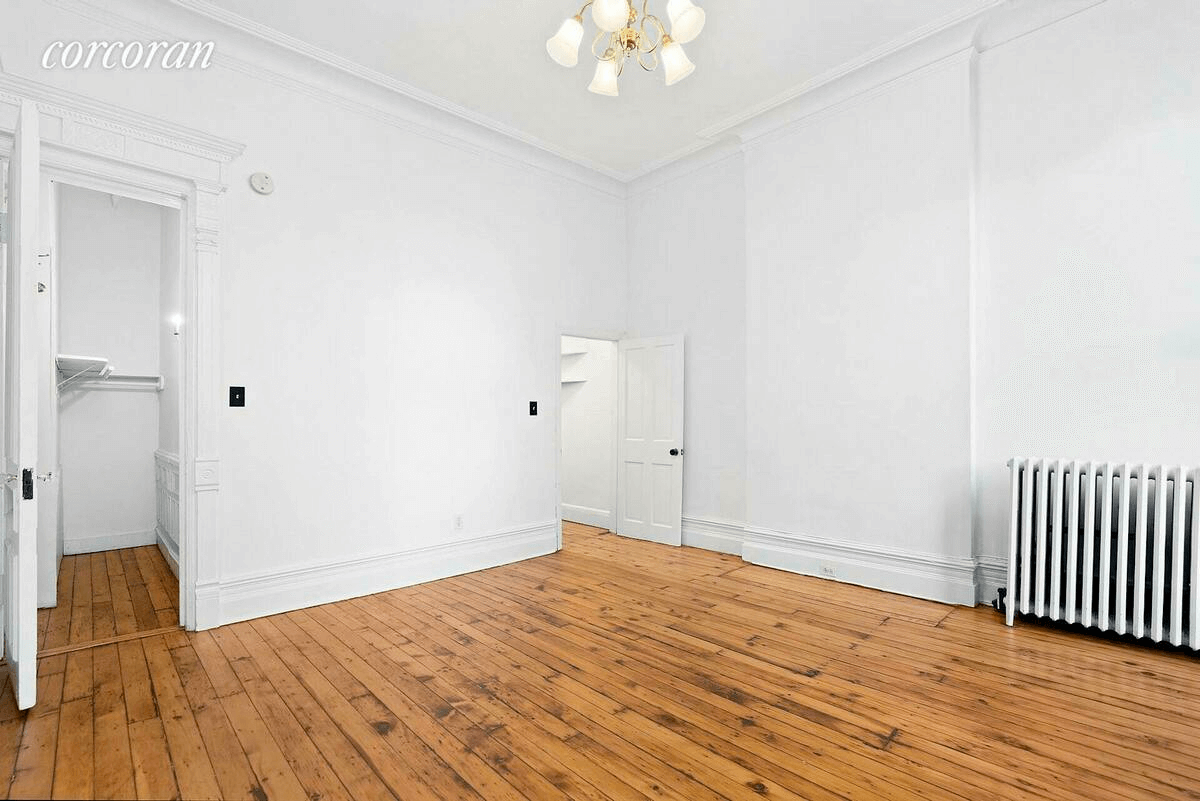 room with crown moldings, wood floor and a closet