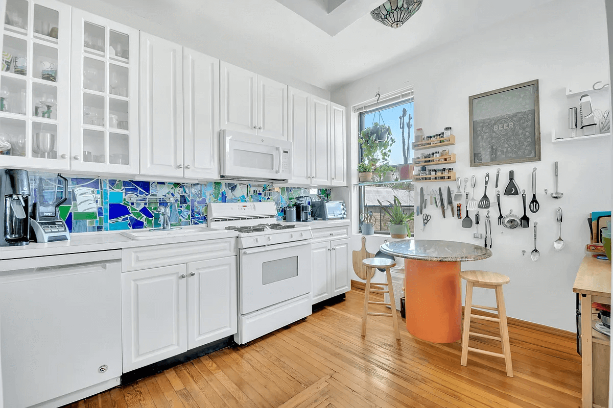 kitchen with a window, white cabinets and blue and green abstract backsplash