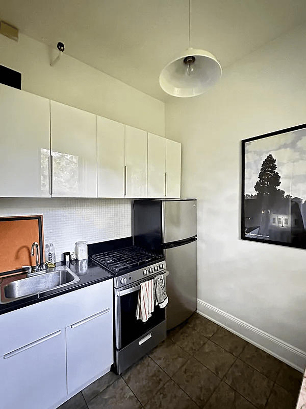 kitchen with glossy white cabinets and a dark tile floor