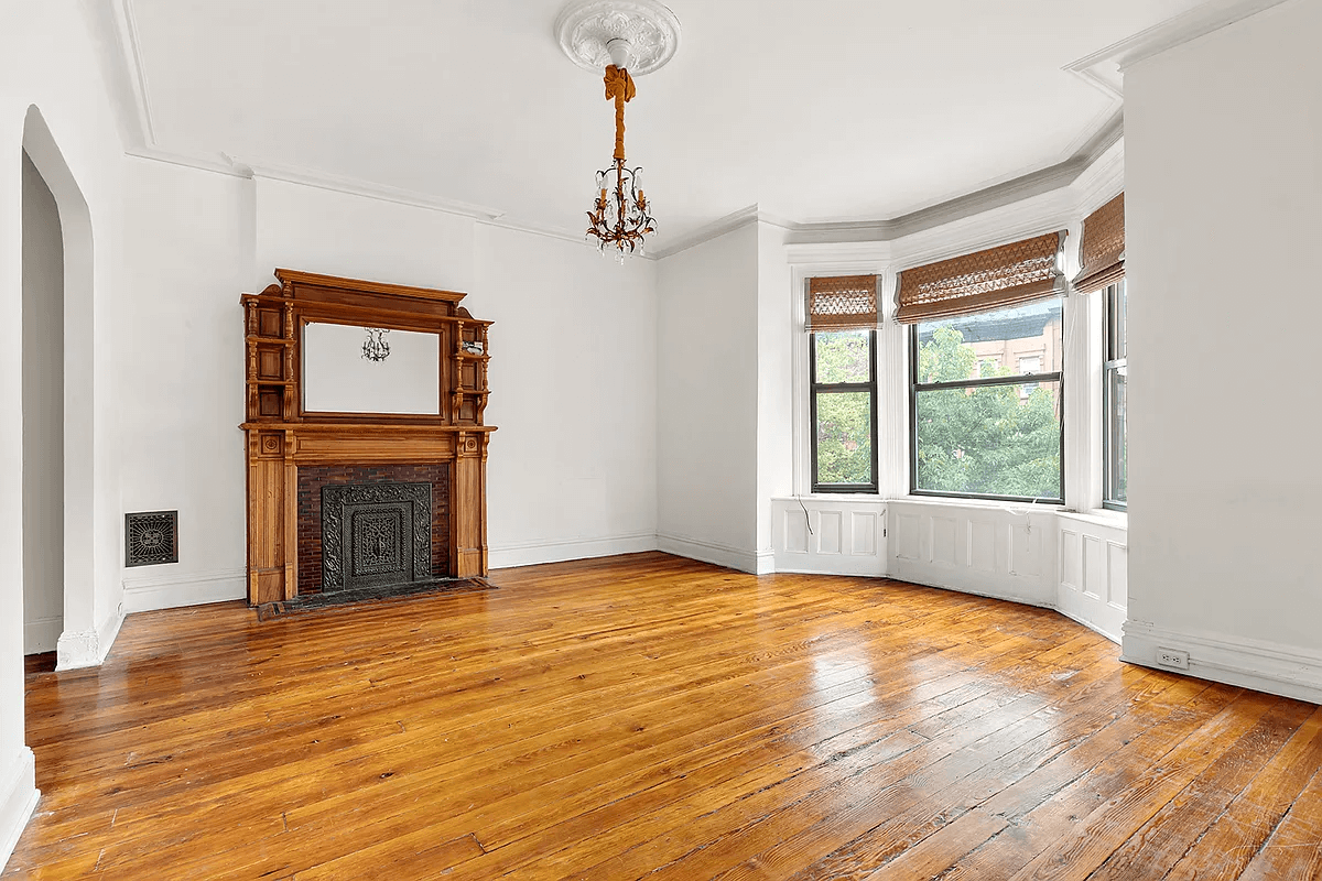 street facing room with wood mantel, moldings and a bay window