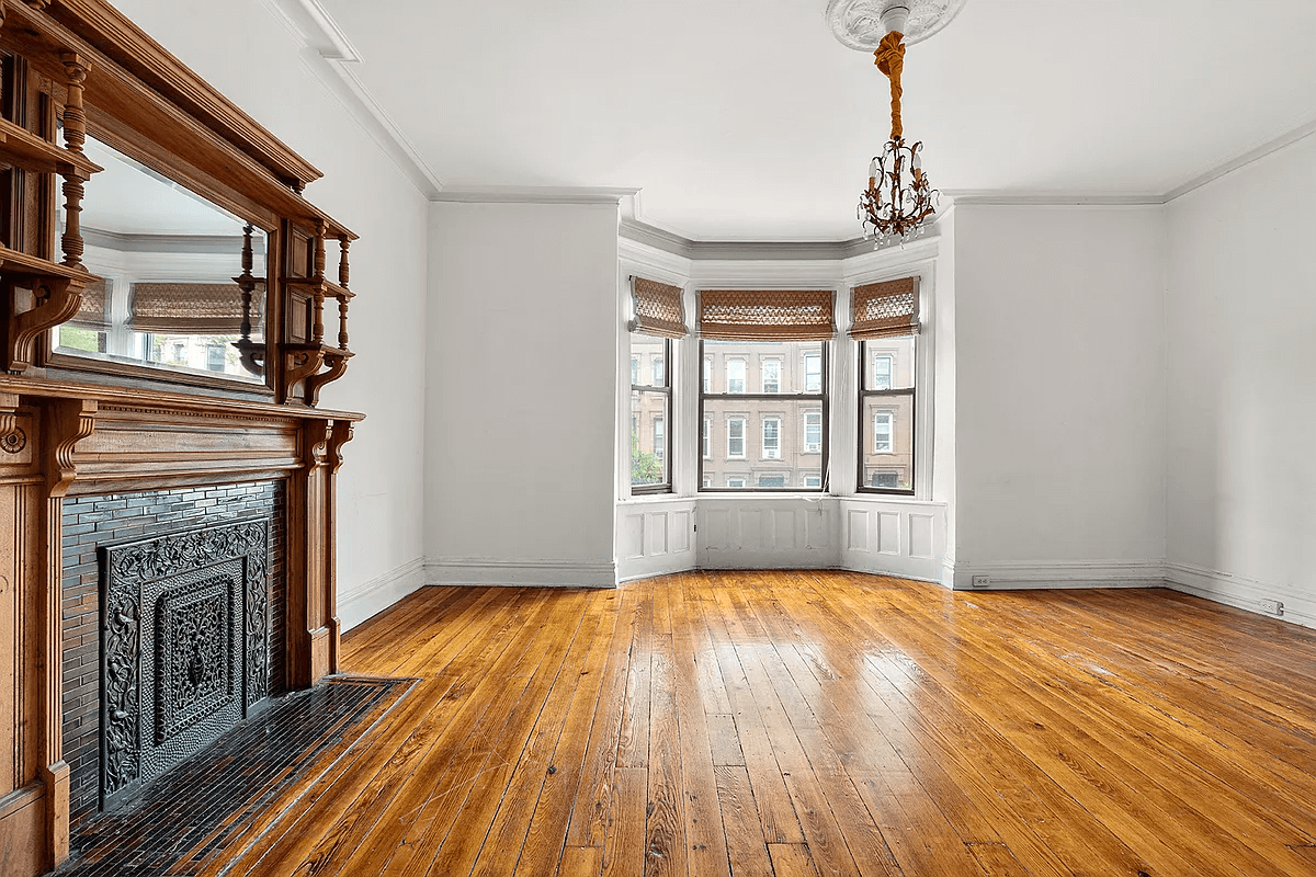 street facing room with wood mantel, moldings and a bay window