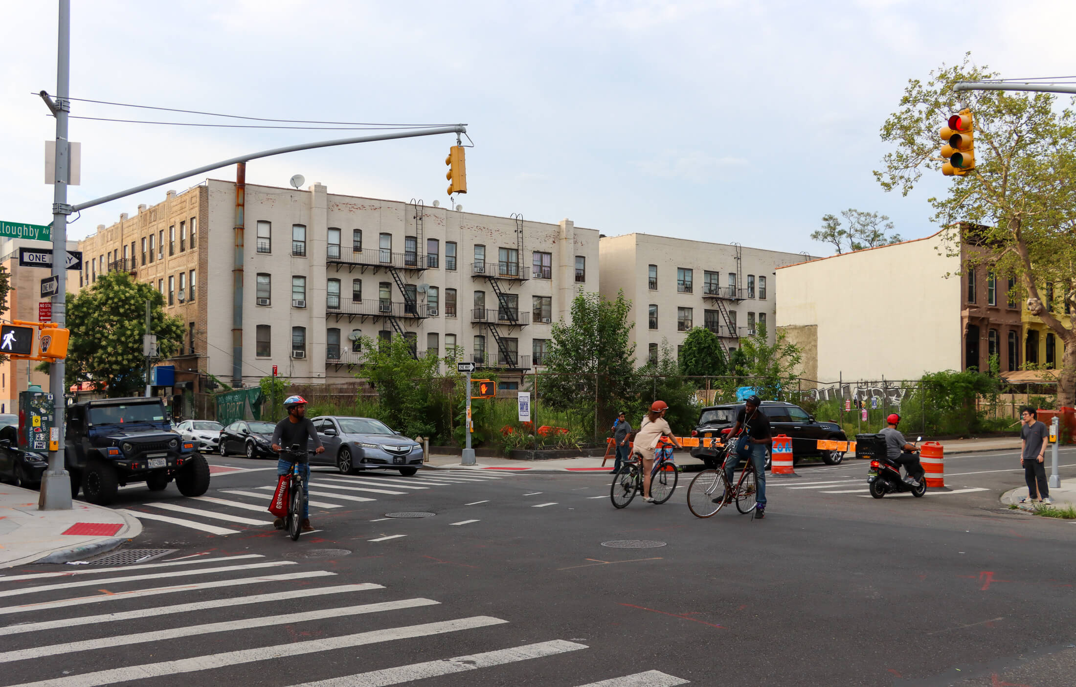 cyclists riding by the empty lot at the corner of Nostrand and Willoughby