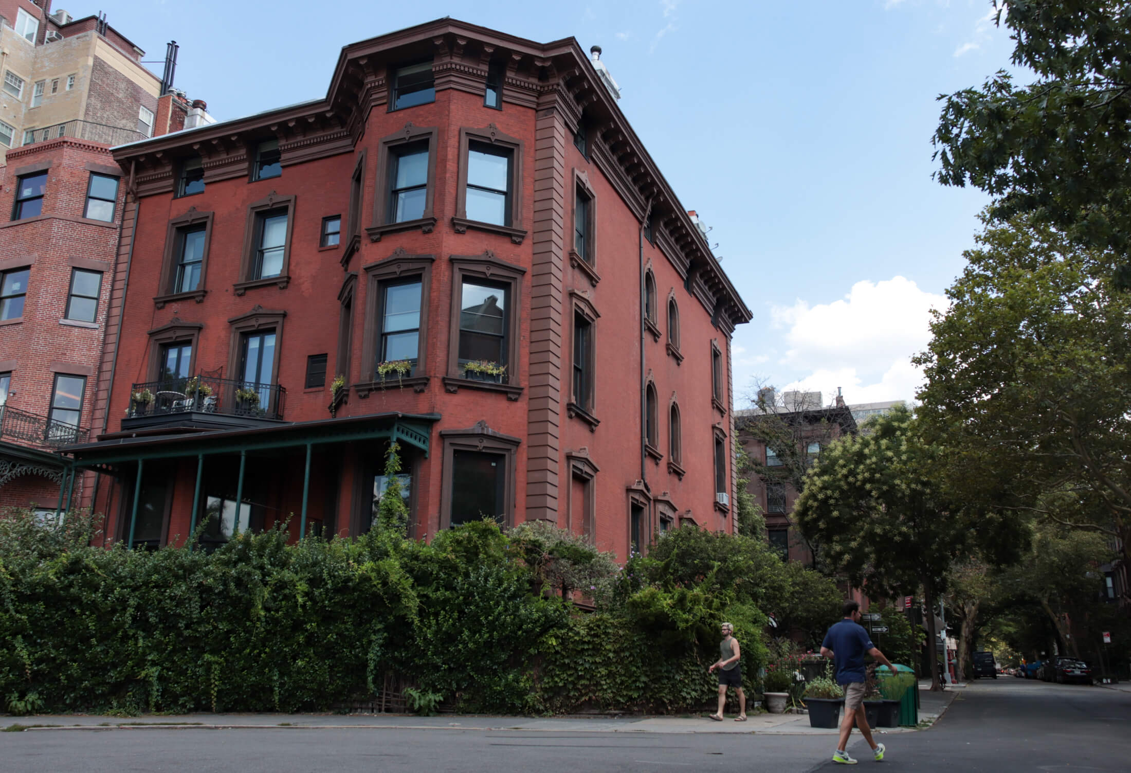 people walking by a historic brick manse that sits near the brooklyn heights promenade