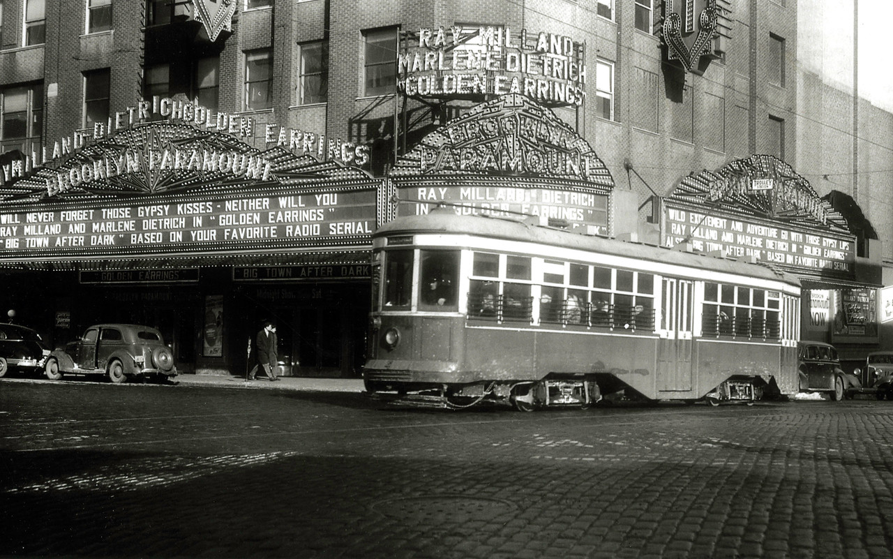 a black and white photo showing a trolley going by the marque