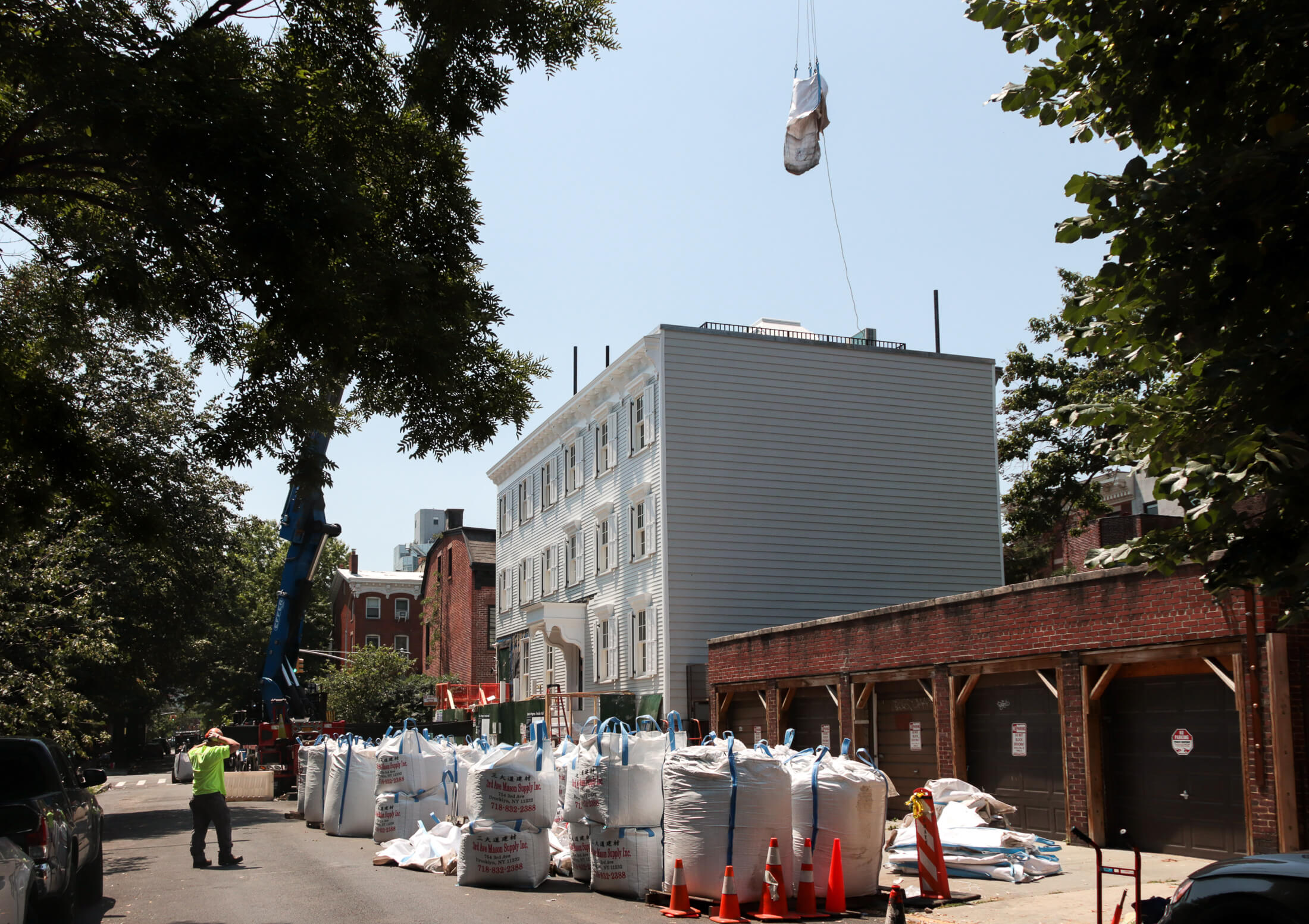 a crane lifts a bag of the roof of the wood frame houses