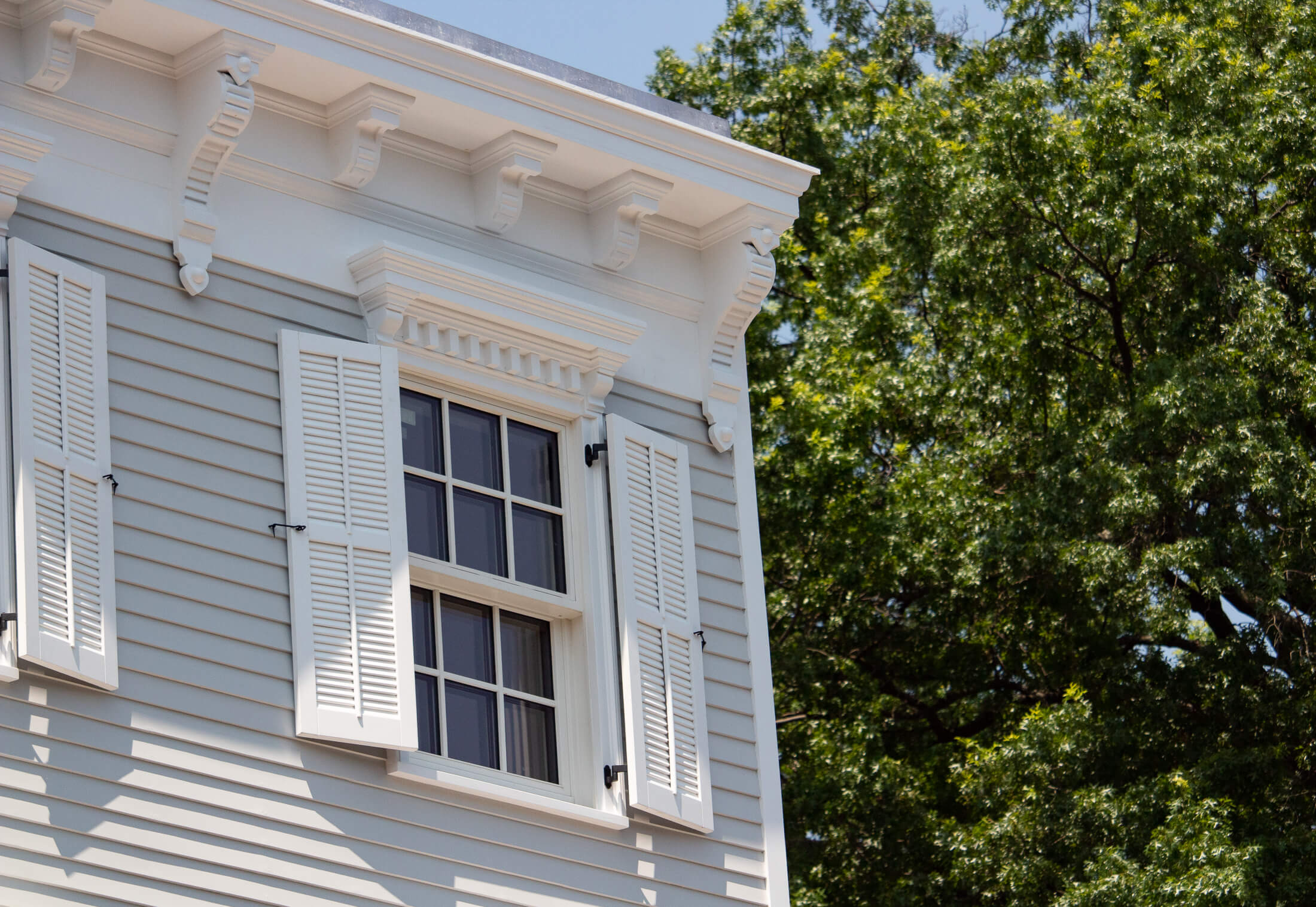 a closeup on the louvered shutters, lintel and cornice