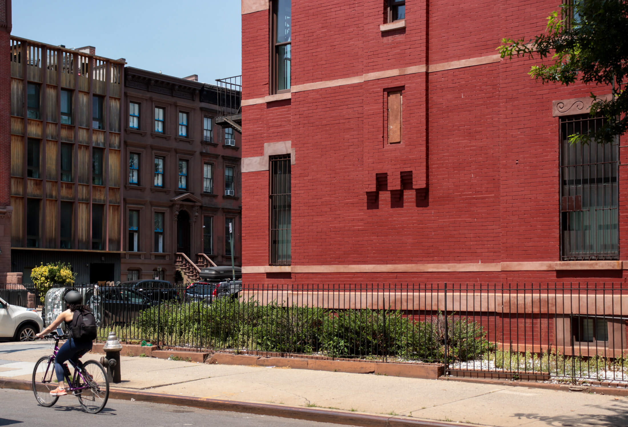 a bike rider passes a brick building with row houses on Washington Avenue in the background