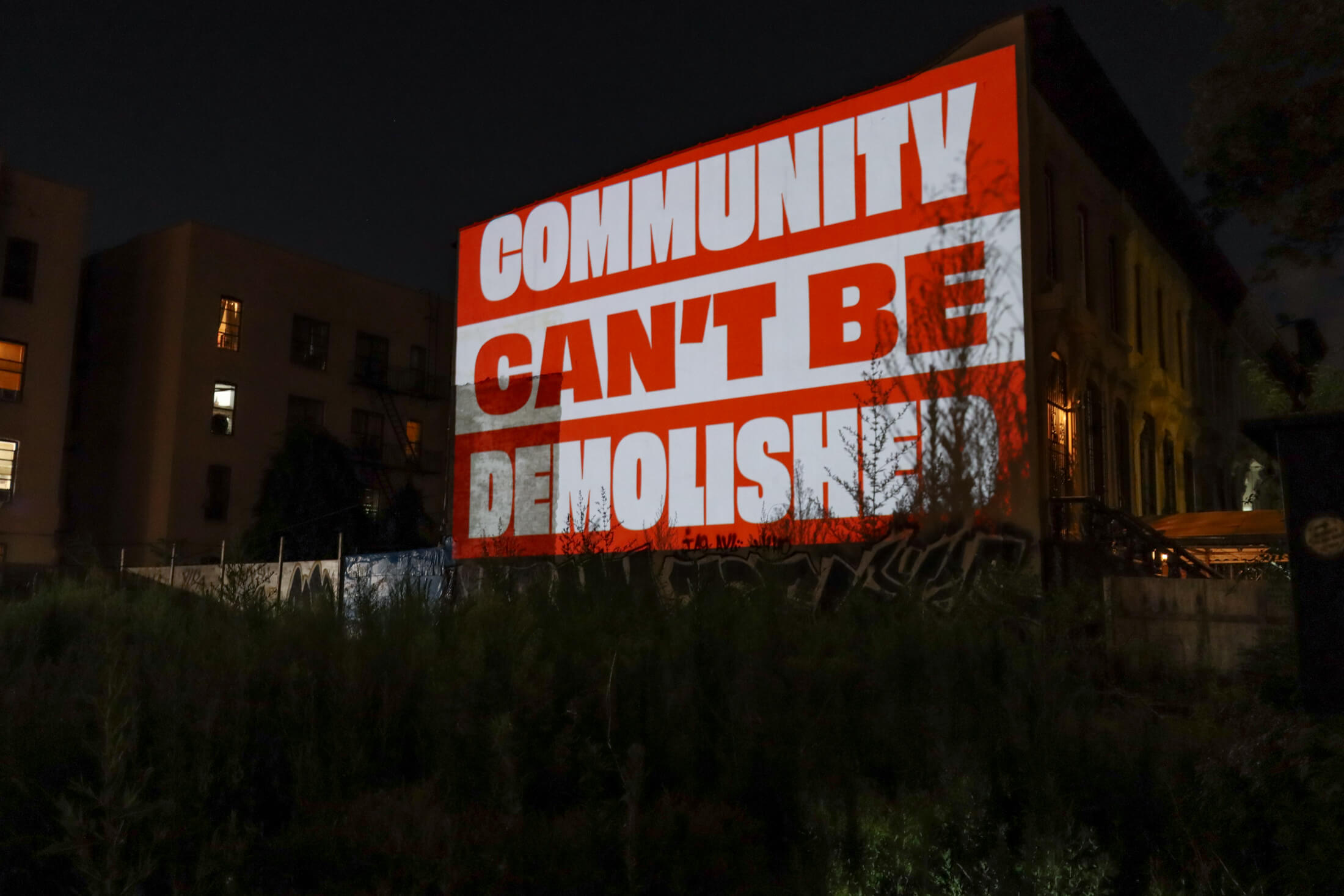 projection of "community can't be demolished" on the site of the demolished dangler mansion