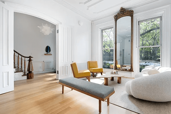 parlor with wood floors, white walls and a view to the original stair