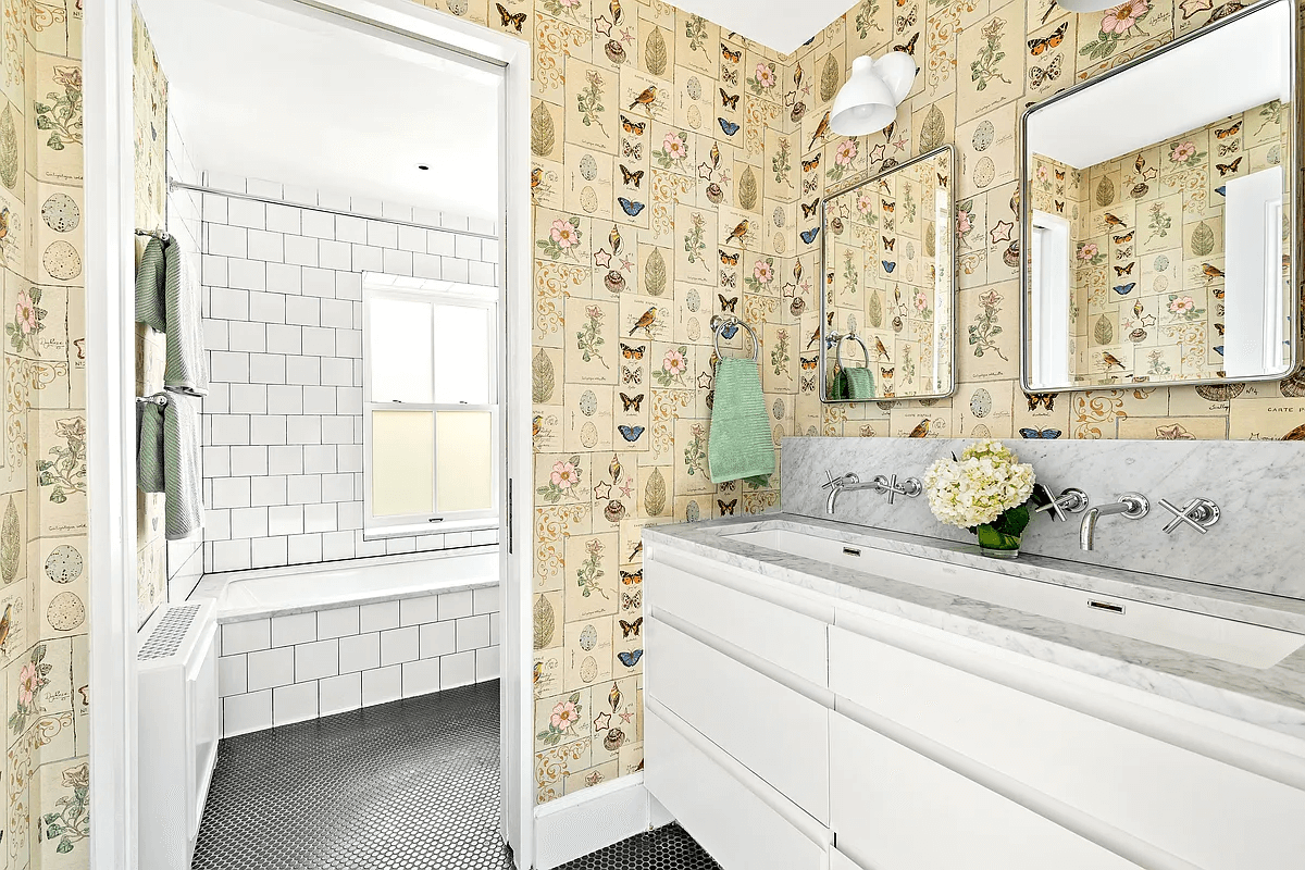 bathroom on the top floor with a double vanity, wallpaper and a black tile floor