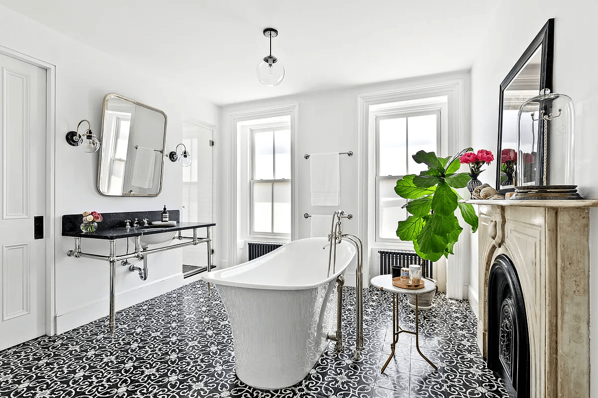 a bathroom with a graphic black and white tile floor, a marble mantel and a white soaking tub