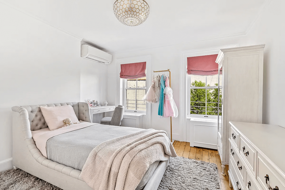 a bedroom with two windows and a wood floor