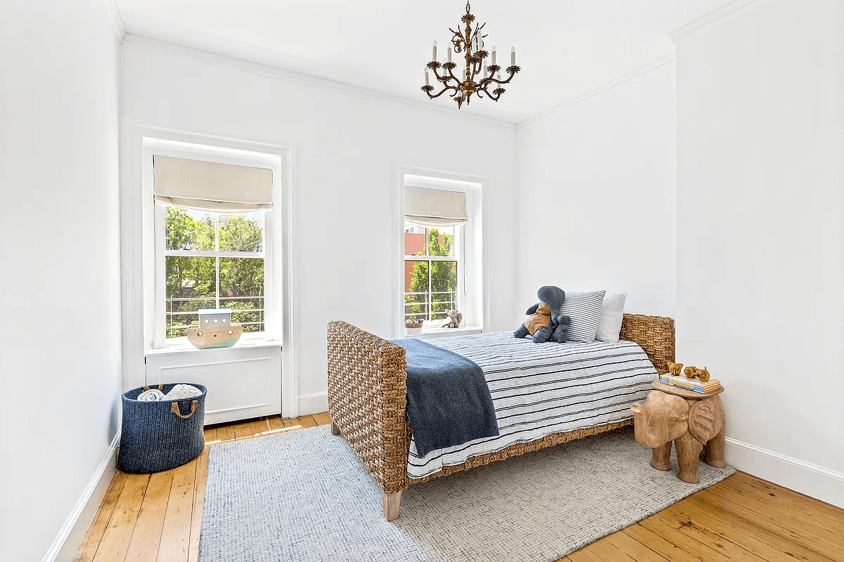 a bedroom with wood floors and two windows