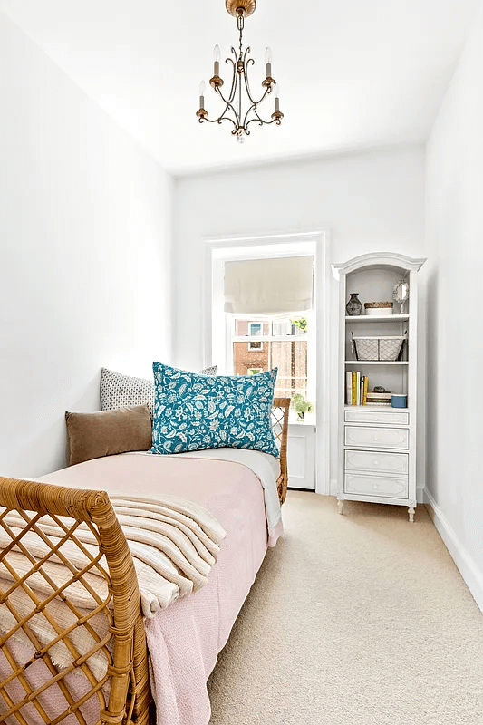 a narrow bedroom with carpeting and a chandelier