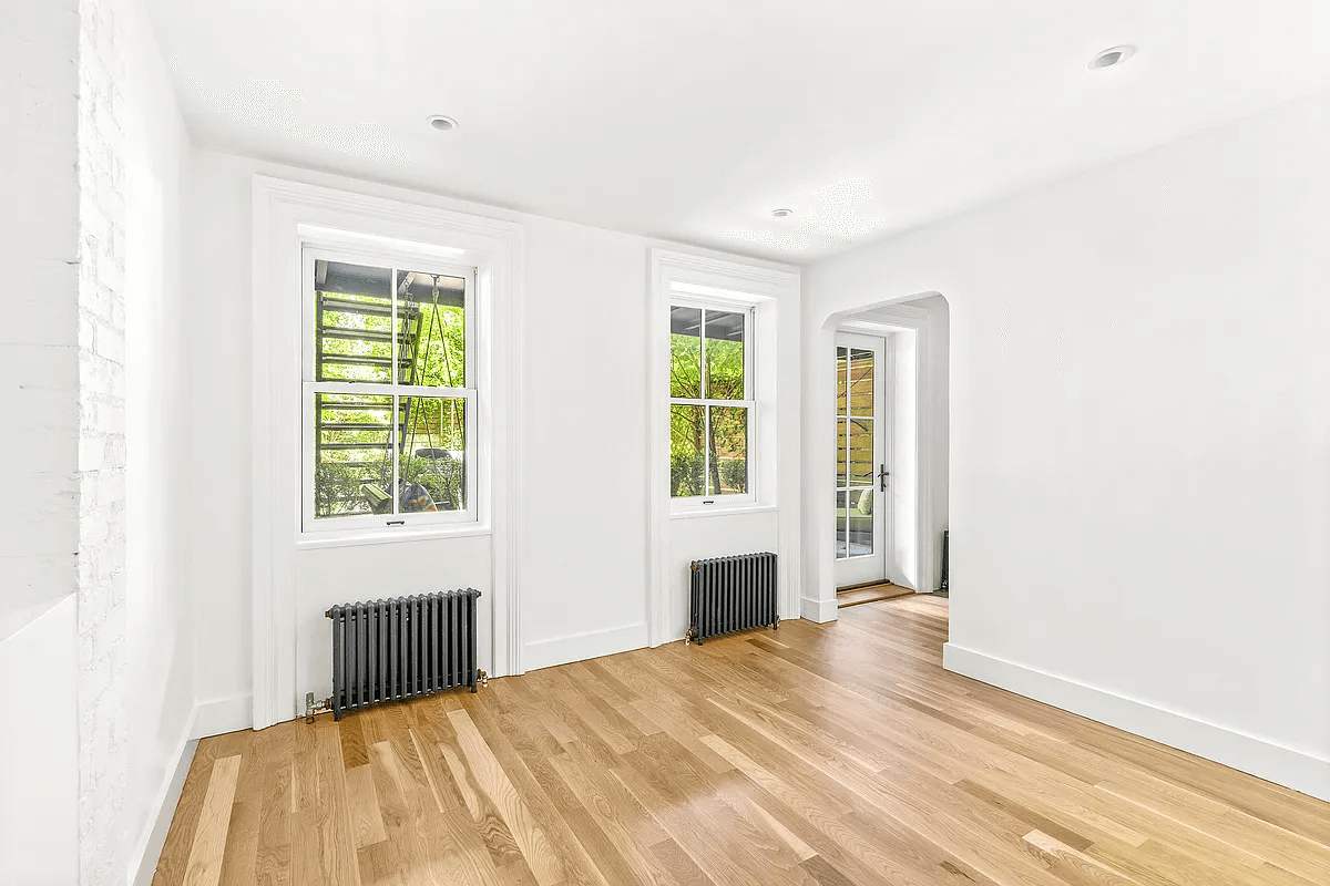 a bedroom in the garden apartment with windows and a door leading to the garden