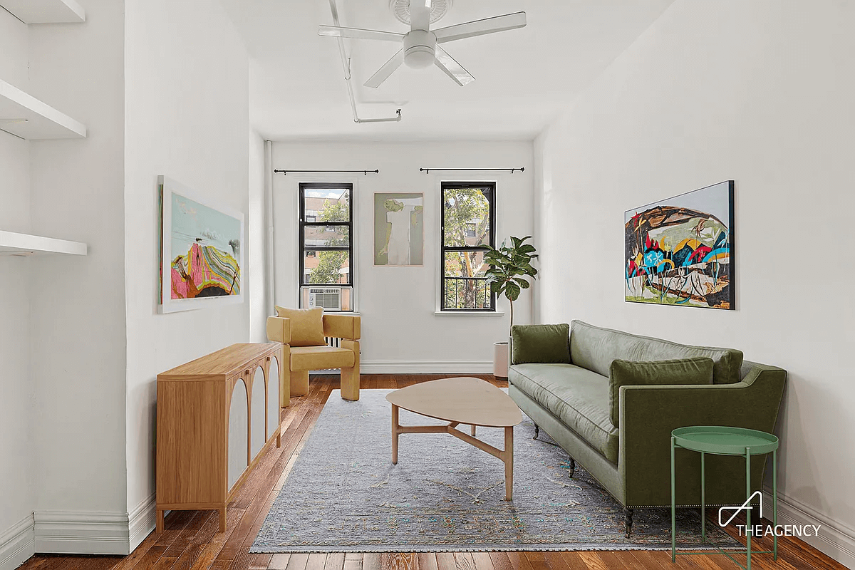 staged view of living room with ceiling fan and two windows