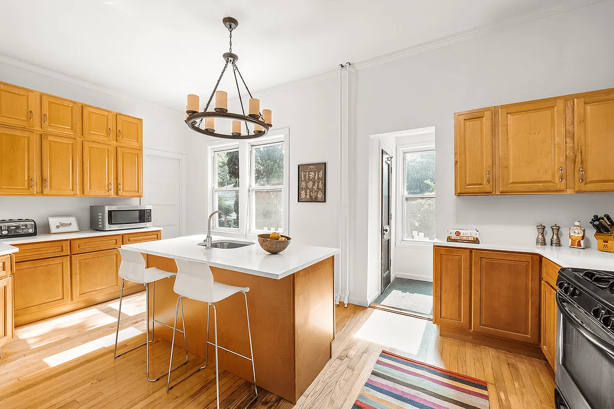 kitchen with wood cabinets, an island and a view of the hall and door to the powder room