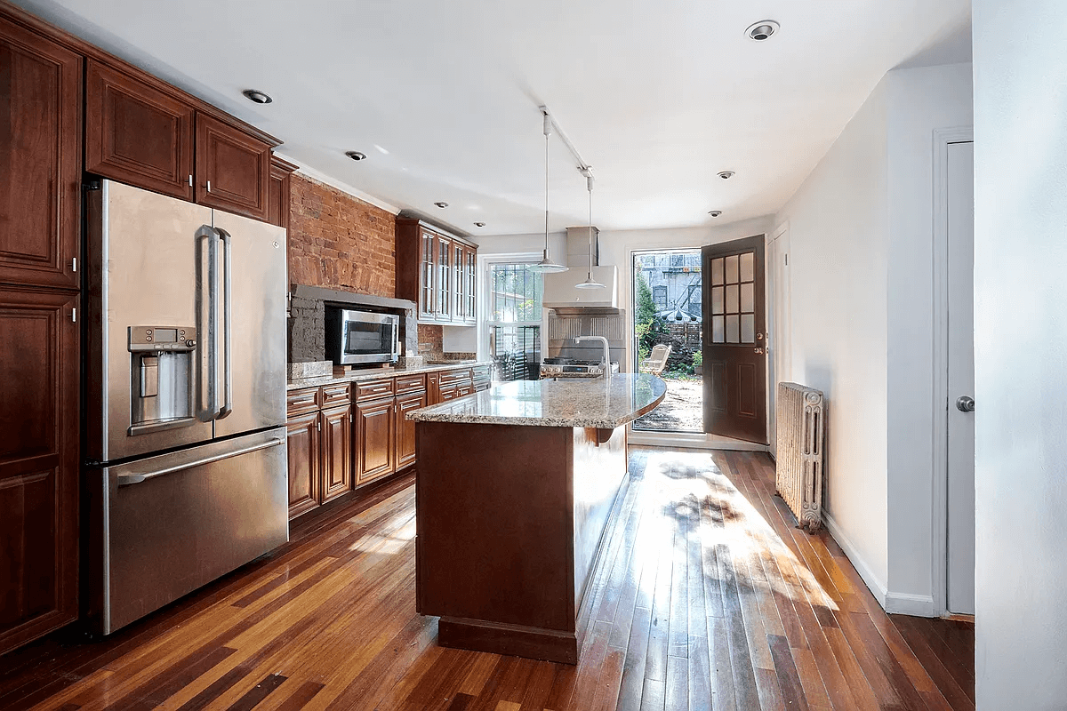 kitchen with a center island, some exposed brick, wood cabinets and a door to the garden