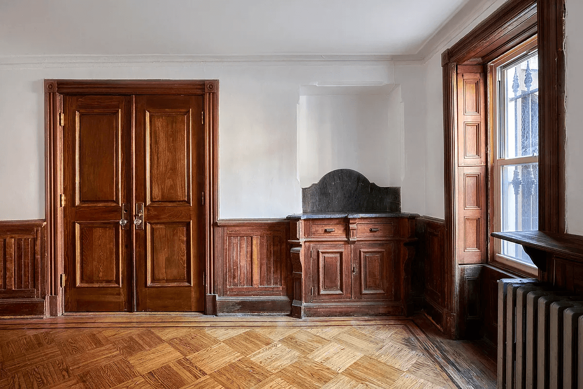 living room with wainscoting, a built-in and window shutters