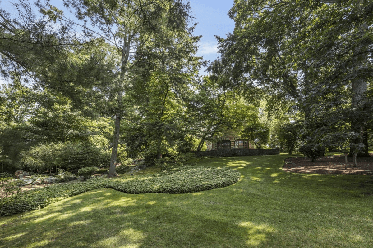 view of lawn with plantings under large trees
