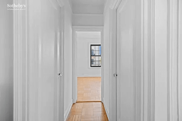 hallway to bedroom with parquet floors and white walls