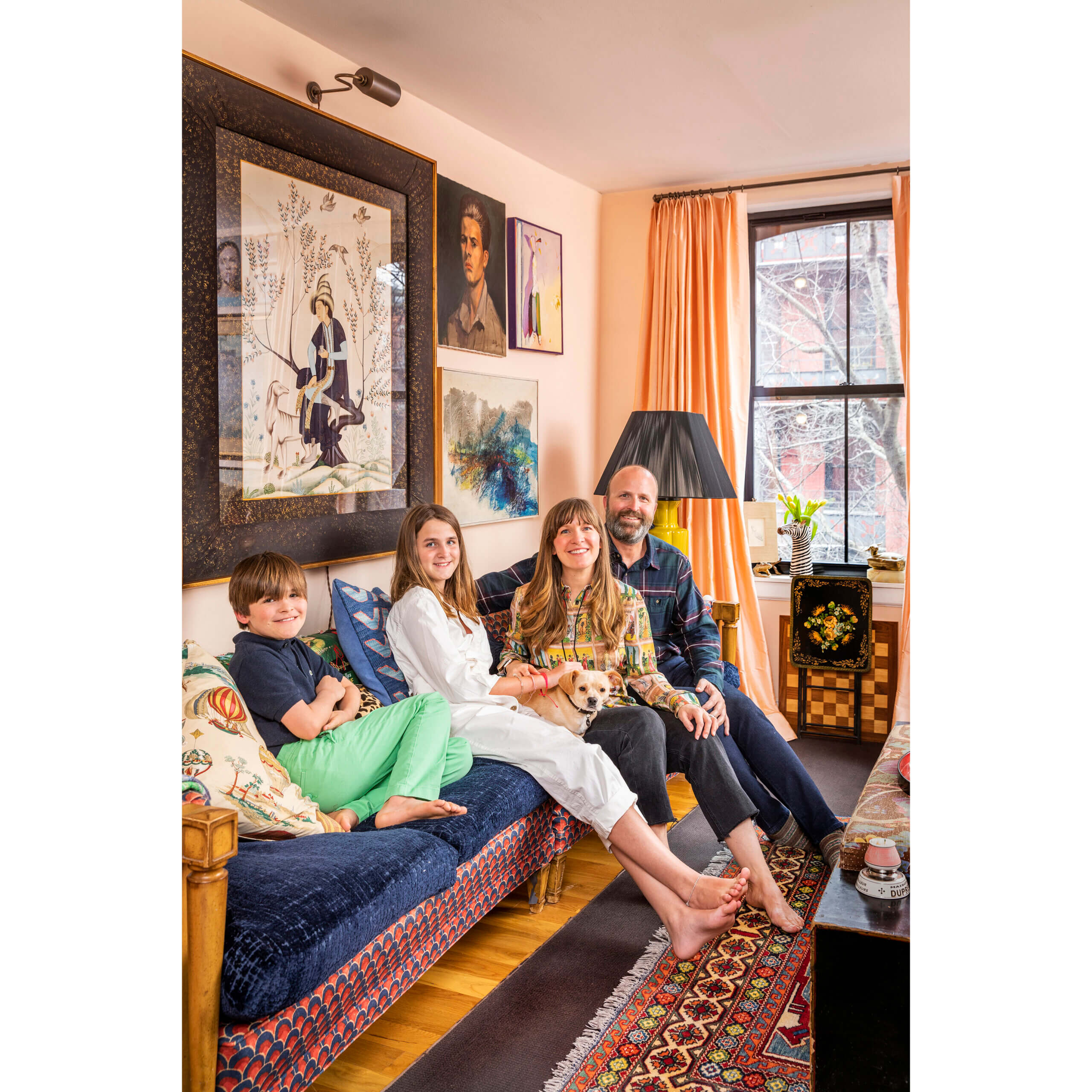 family of four and their dog sitting on a large sofa