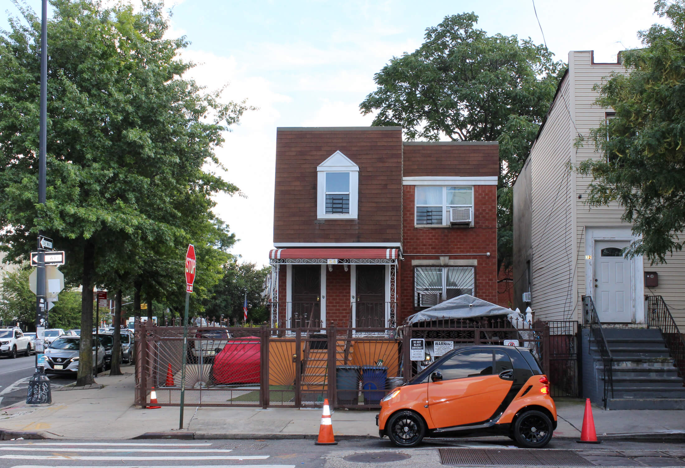 brooklyn - tiny orange smart car parked in front of a petite house