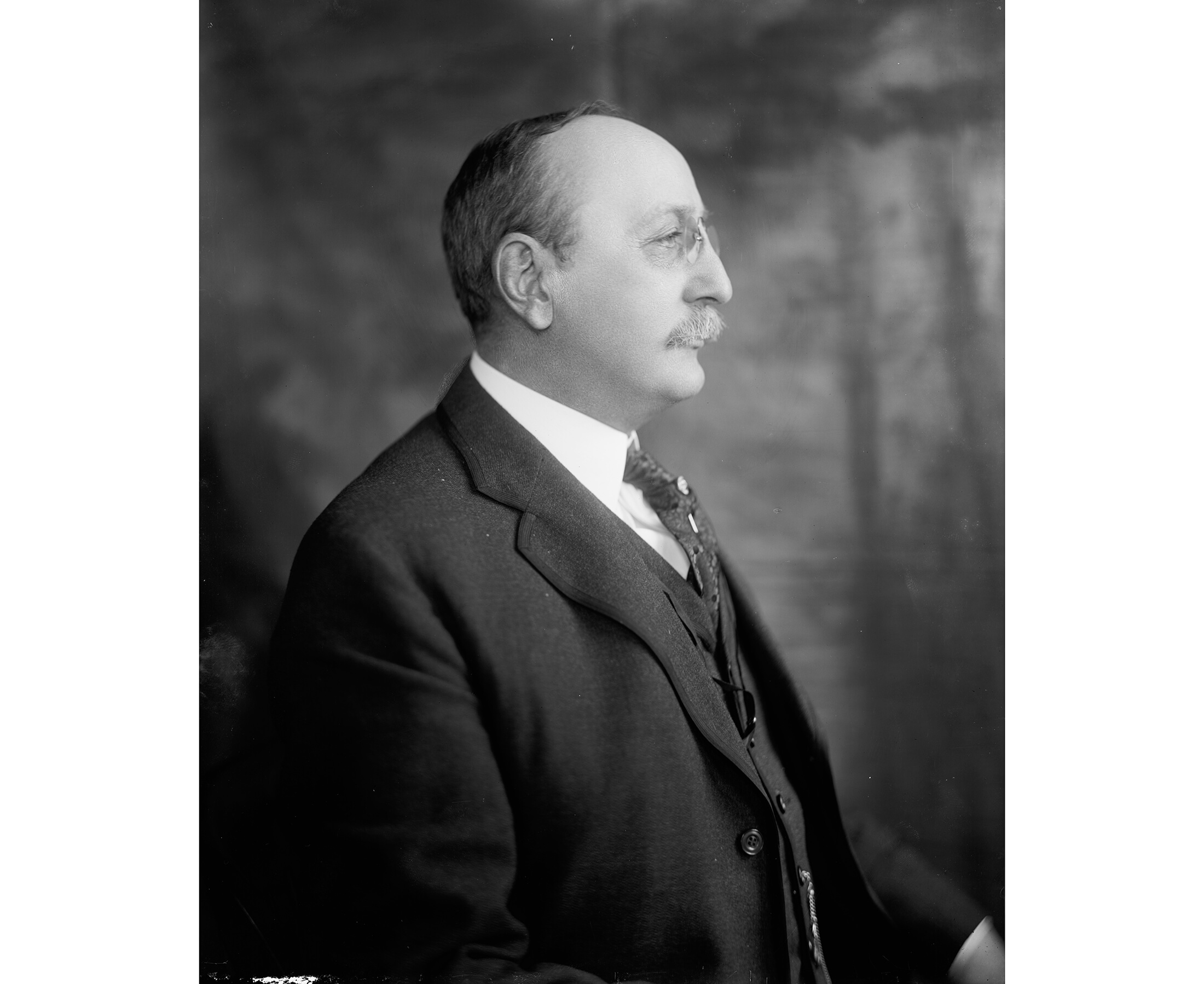 a black and white profile portrait of gilbert in a suite and tie
