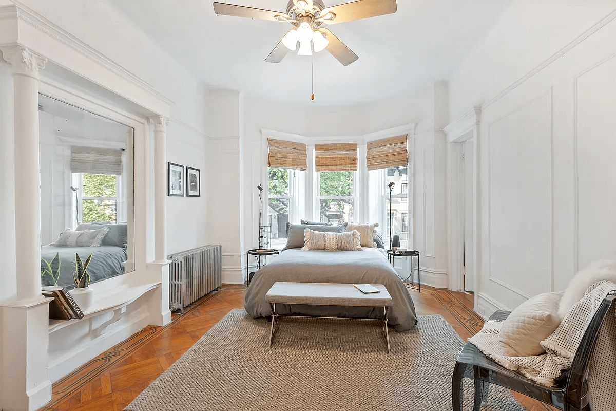 bedroom with a pier mirror, wall moldings and a ceiling fan