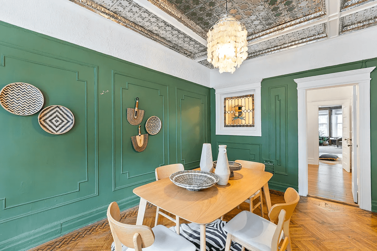 dining room with green walls, wall moldings and a tin ceiling