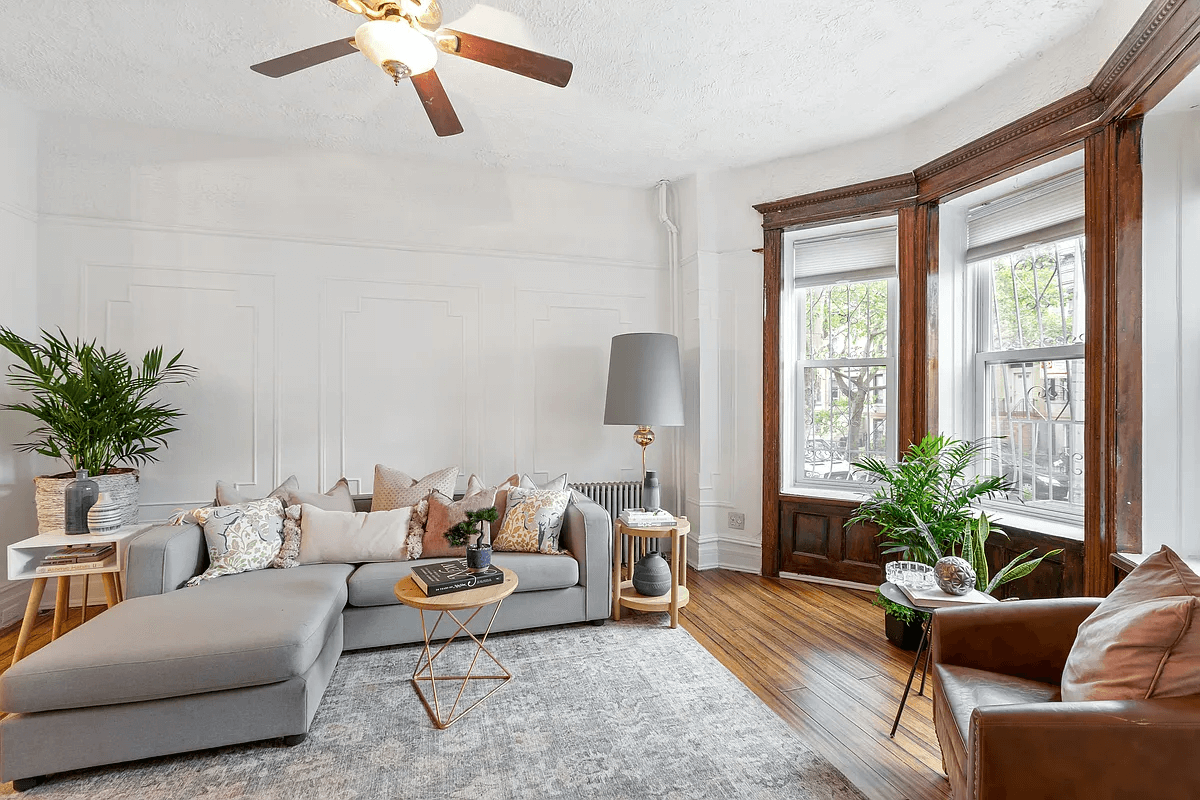 living room with bay window, wall moldings and wood floors