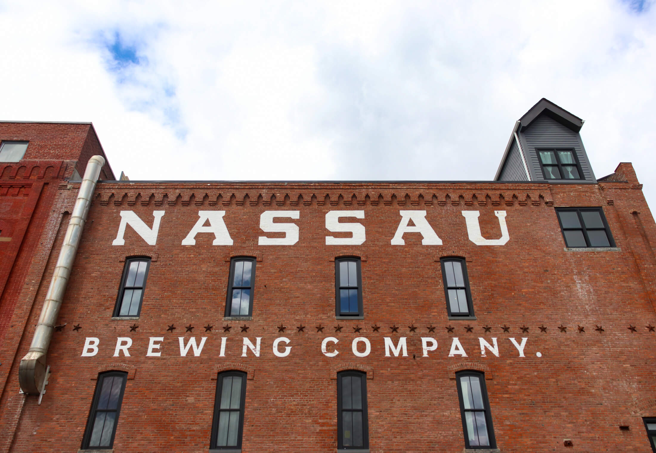 the white painted nassau brewing company sign on the exterior of the building