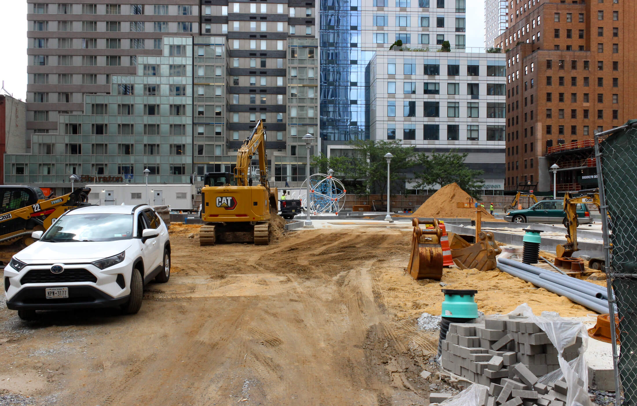 view from albee showing piles of construction materials and a glimpse of playground equipment