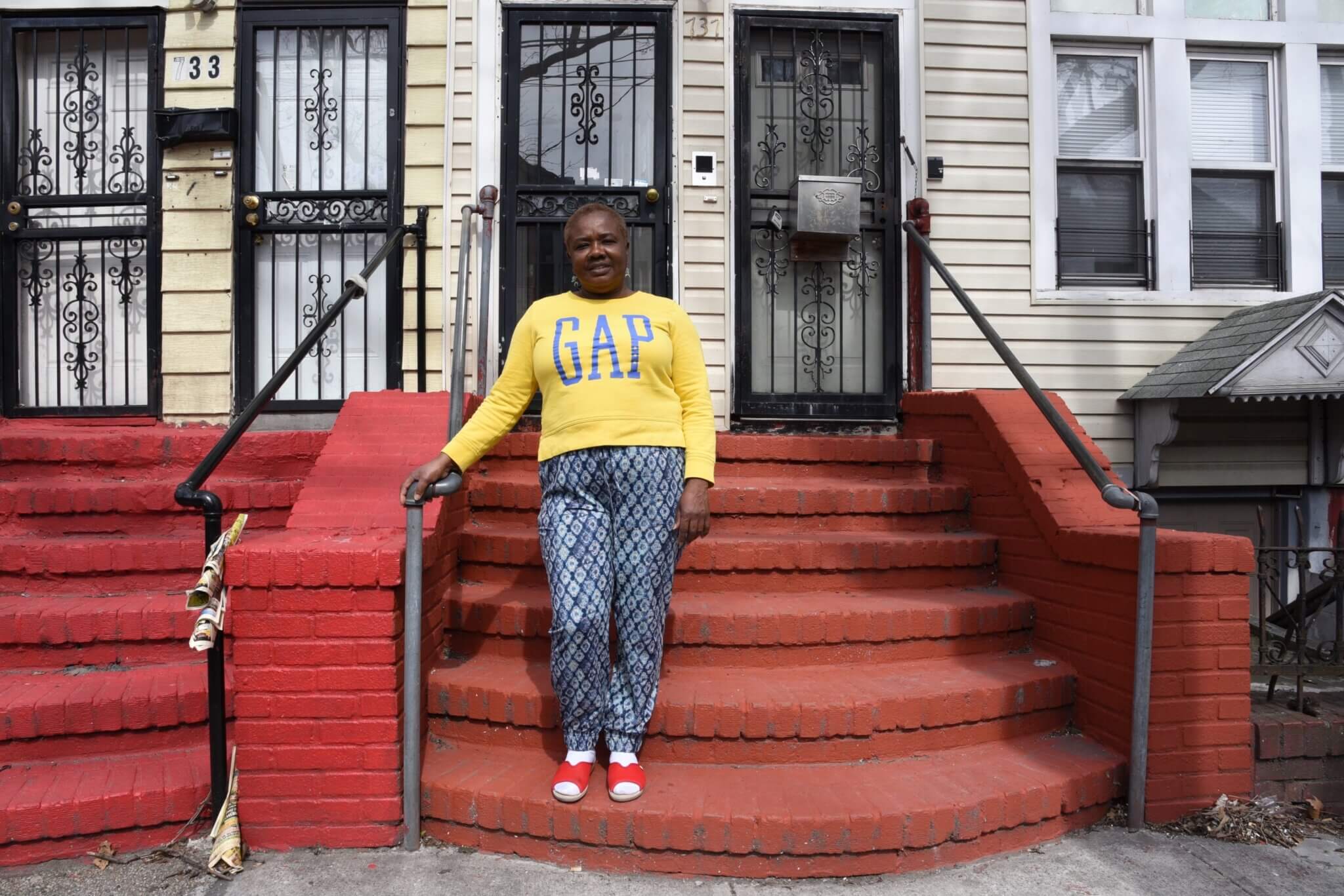 woman standing on the brick steps outside of a vinyl sided building